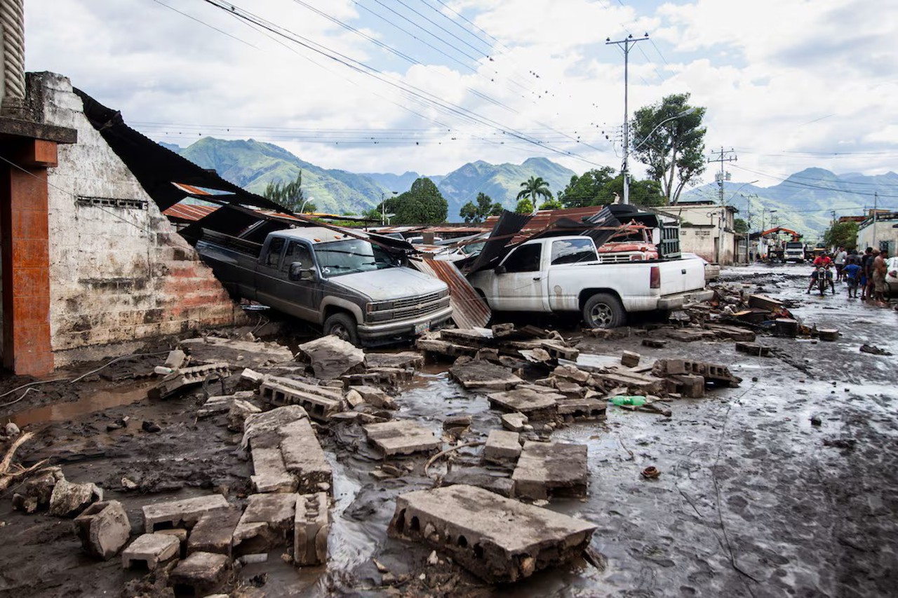 Reuters / Oamenii se plimbă pe lângă vehiculele avariate după ce inundațiile devastatoare au măturat orașul după trecerea uraganului Beryl de pe coasta venezueleană, în Cumanacoa, 2 iulie 2024