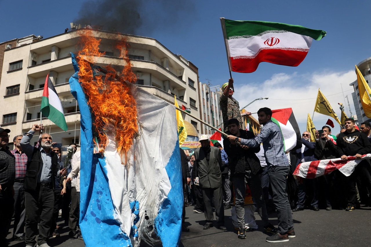 Reuters / Iranieni ard un steag israelian în timpul unui miting care marchează Ziua Quds și înmormântarea membrilor Corpului Gărzilor Revoluționare Islamice care au fost uciși într-un presupus atac aerian israelian asupra complexului ambasadei iraniene din capitala siriană Damasc. Teheran, Iran, 5 aprilie 2024